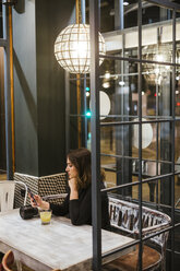 Young woman with camera and cell phone in a bar at night - LJF00099