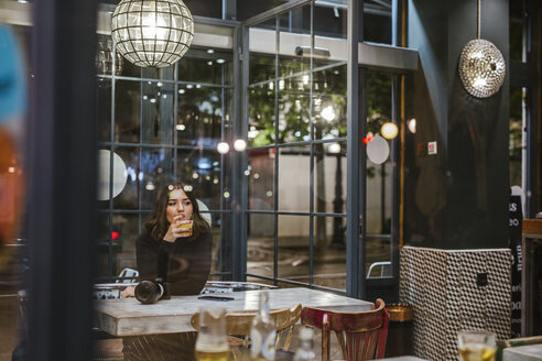 Junge Frau mit Kamera in einer Bar bei Nacht - LJF00103