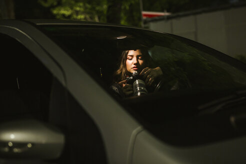 Junge Frau mit Kamera in einem Auto bei Nacht - LJF00109