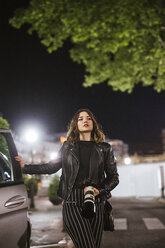 Young woman with camera at a car at night - LJF00111