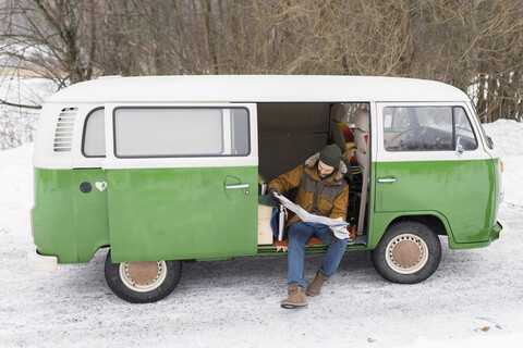 Mann mit Elektrotransporter in Winterlandschaft beim Studium der Straßenkarte, Kuopio, Finnland, lizenzfreies Stockfoto