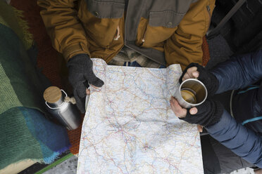 Paar mit heißem Getränk und Winterkleidung studiert Straßenkarte - PSIF00283