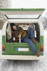 Glücklicher Mann mit elektrischem Lieferwagen in Winterlandschaft bei einer Pause, Kuopio, Finnland - PSIF00284