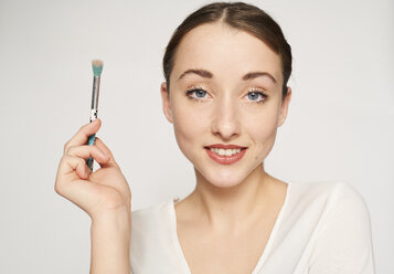 Portrait of smiling young woman with beauty brush - PNEF01536