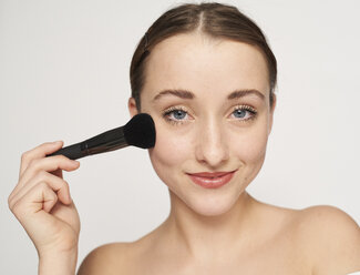 Portrait of smiling young woman with beauty brush - PNEF01538