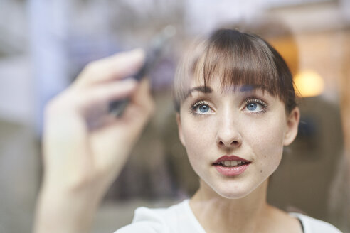 Portrait of young businesswoman writing on glass pane - PNEF01555