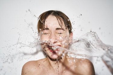 Porträt einer lachenden jungen Frau mit spritzendem Wasser - PNEF01557