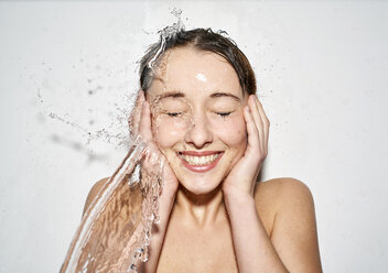 Porträt einer lachenden jungen Frau mit spritzendem Wasser - PNEF01560