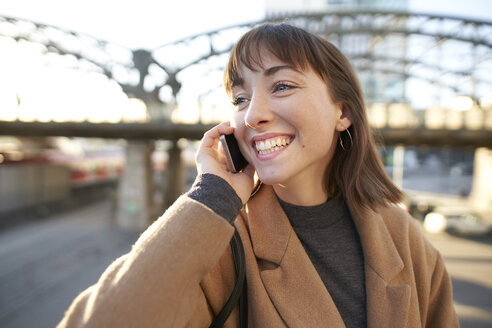 Porträt einer glücklichen jungen Geschäftsfrau, die im Freien telefoniert - PNEF01562