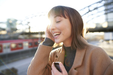 Portrait of happy young businesswoman with smartphone outdoors - PNEF01563