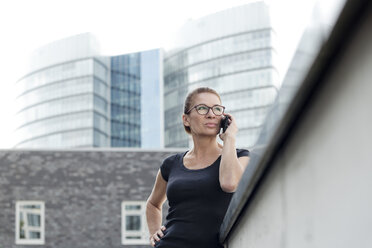 Frau am Handy vor einem Bürogebäude - FLLF00226