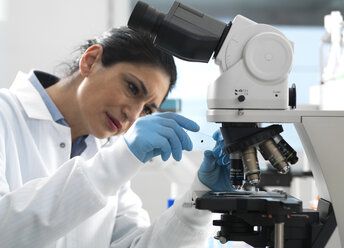 Lab technician examing a glass slide containing a blood sample ready to be magnified under the microscope in the laboratory - ABRF00392