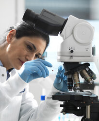 Labortechniker bei der Untersuchung eines Objektträgers mit einer Blutprobe, die unter dem Mikroskop im Labor vergrößert werden soll - ABRF00393