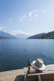 Man resting at lakeshore, Seeboden, Millstatt Lake, Carinthia, Austria - GWF06098