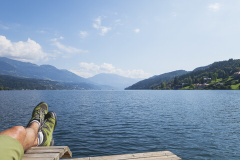 Beine eines Mannes, der am Seeufer ruht, Seeboden, Millstätter See, Kärnten, Österreich, lizenzfreies Stockfoto