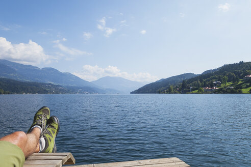 Beine eines Mannes, der am Seeufer ruht, Seeboden, Millstätter See, Kärnten, Österreich - GWF06099