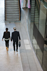 Rear view of male and female colleagues walking in lobby - MASF12379