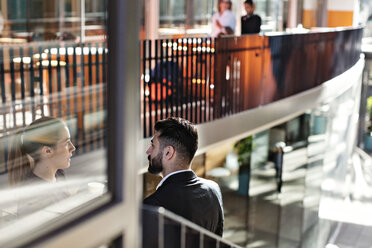 Geschäftsleute diskutieren auf einer Treppe im Büro stehend - MASF12405