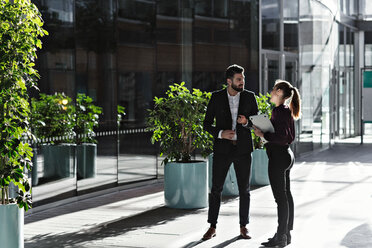 Male and female colleagues discussing in office lobby - MASF12417