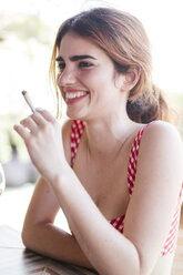 Porträt einer glücklichen, zufriedenen Frau, die im Freien eine Zigarette raucht - LJF00121