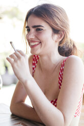 Portrait of happy happy woman smoking a cigarette outdoors - LJF00121