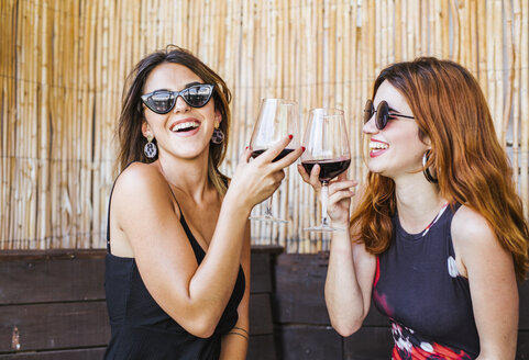 Two happy women having a glass of red wine at a bar - LJF00123