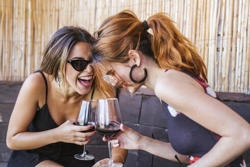 Zwei glückliche Frauen trinken ein Glas Rotwein in einer Bar - LJF00126