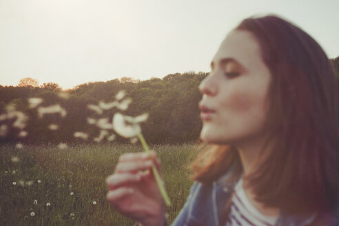 Portrait of teenage girl blowing blowball - ANHF00112