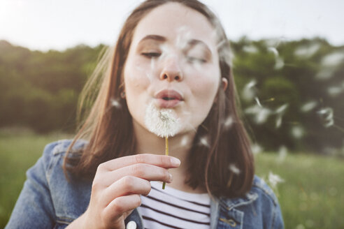 Portrait of teenage girl blowing blowball - ANHF00114
