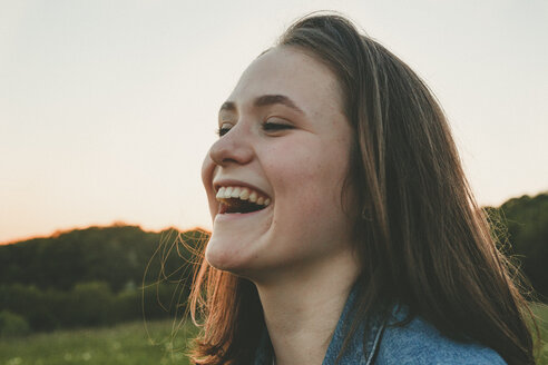 Portrait of laughing teenage girl in nature at sunset - ANHF00124