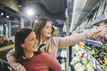 Lächelnde Mutter nimmt ihre Tochter beim Einkaufen im Supermarkt huckepack - MASF12431