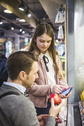 Niedliche Tochter zeigt dem Vater das Handy beim Einkaufen im Supermarkt - MASF12439