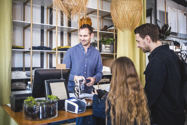 Vater und Tochter stehen an der Kasse einer Boutique - MASF12460