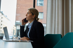 Selbstbewusster Immobilienmakler, der im Büro mit seinem Smartphone telefoniert - MASF12477