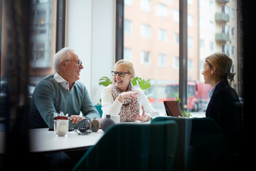 Lächelndes älteres Ehepaar im Gespräch mit einem Immobilienmakler im Büro - MASF12487