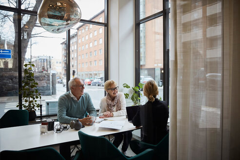 Smiling senior couple discussing with female realtor in estate office - MASF12491