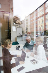 Smiling senior couple signing document while sitting with agent in real estate office - MASF12493