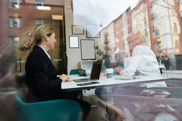 Smiling real estate agent looking at elderly couple talking in office - MASF12495