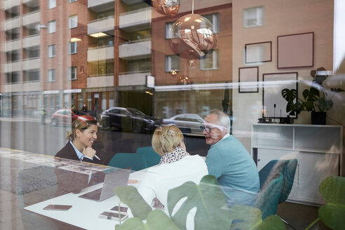 Smiling estate agent advising senior couple while sitting in office - MASF12496