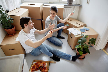 Couple discussing over color swatches while having pizza at new home - MASF12504