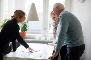 Ein Immobilienmakler erklärt einem älteren Ehepaar die Unterlagen für ein neues Haus - MASF12519