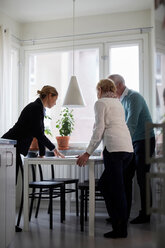 Immobilienmakler in voller Länge, der einem älteren Ehepaar die Unterlagen für das neue Haus erläutert - MASF12523