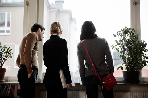 Immobilienmakler und Kunden schauen durch das Fenster eines neuen Hauses, lizenzfreies Stockfoto