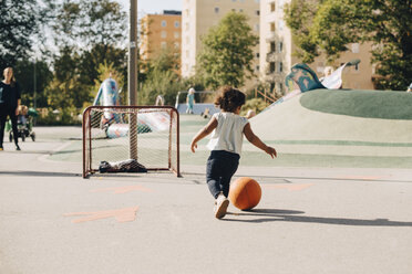 Full length of girl playing with ball on playground at city - MASF12545