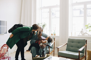 Couple kissing while daughter drinking milk in living room at home - MASF12566