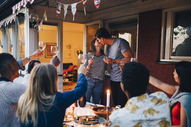 Man and woman kissing during dinner party with friends - MASF12624