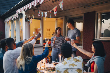 Männliche und weibliche Freunde jubeln mit Weingläsern während einer Dinnerparty - MASF12629