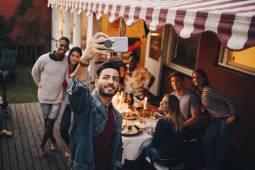 Lächelnder junger Mann macht Selfie mit Freunden während einer Dinnerparty - MASF12631