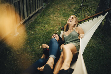 High angle view of cheerful female friends with lying on hammock at yard - MASF12648