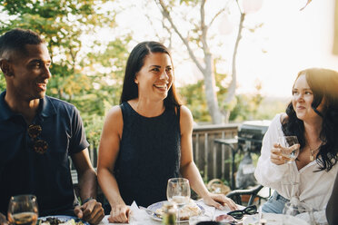 Lächelnde männliche und weibliche Freunde, die das Essen am Esstisch in einer Dinnerparty genießen - MASF12659